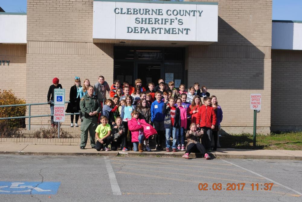 Students posing with a member of the Sheriff's Department in front of the Cleburne County Sheriff's office.