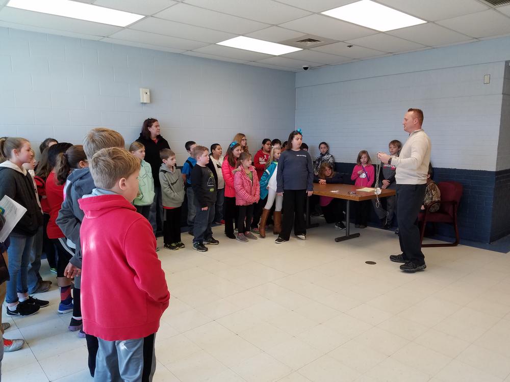 Students on their tour being shown a set of handcuffs from a member of the Sheriff's Department.