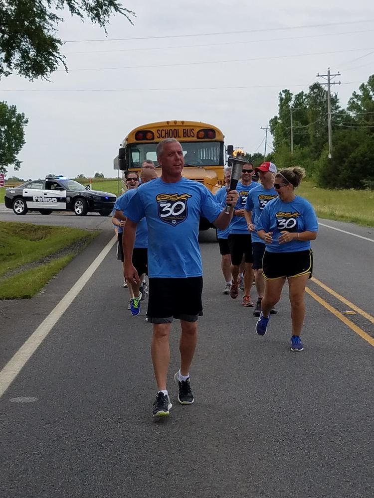 Older gentleman holding the torch and taking his turn as leader of the group during the run.