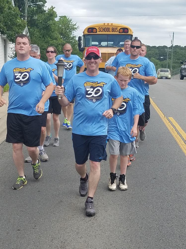 Sheriff Chris Brown holding the torch leading the froup in the Law Enforcement Torch Run for Special Olympics. 