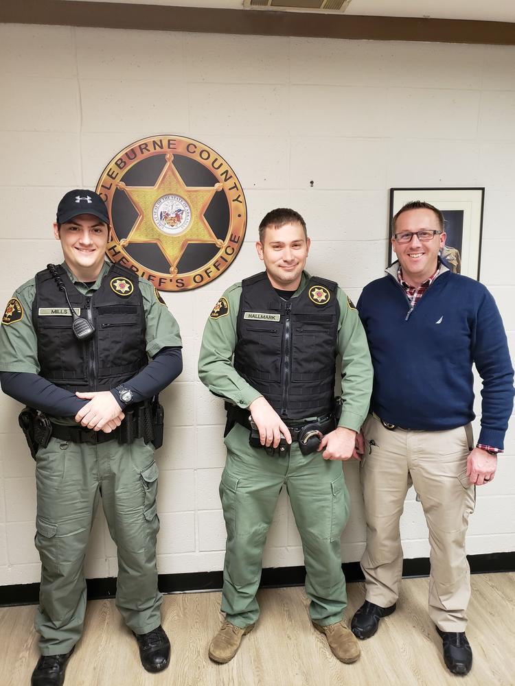 Two deputies wearing the new carriers alongside Sheriff Chris Brown.